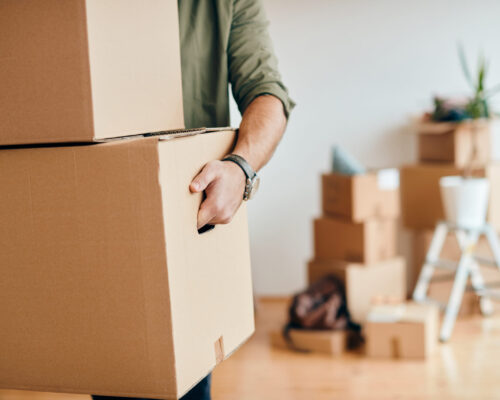 Close-up of a man with carton boxes moving into new home.