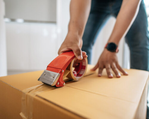 Close up hand of man use glue tape to close cardboard box, sealing big box for packing moving, new house concept, Selective focus	cardboard box,